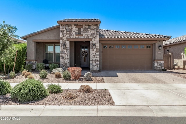 mediterranean / spanish home featuring a tiled roof, an attached garage, stucco siding, driveway, and stone siding