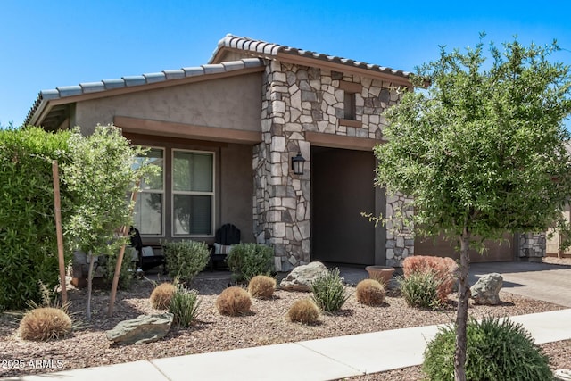 view of front facade featuring driveway, stucco siding, a garage, and stone siding