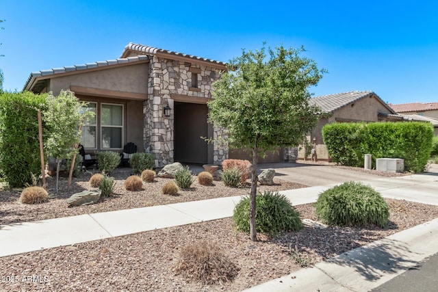 view of front facade with concrete driveway, stucco siding, a tiled roof, and stone siding