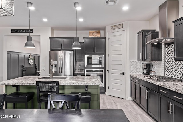 kitchen with stainless steel appliances, wall chimney range hood, a kitchen breakfast bar, backsplash, and recessed lighting