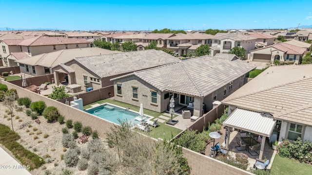 rear view of house featuring a fenced backyard, a residential view, a tile roof, and a patio