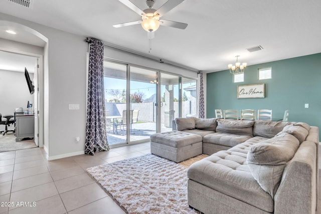 tiled living room with ceiling fan with notable chandelier