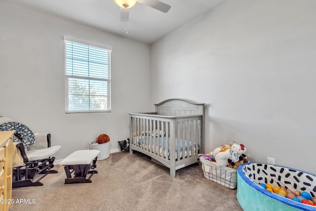 bedroom with a nursery area, ceiling fan, and carpet flooring