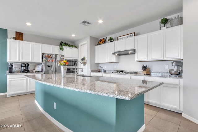 kitchen with stainless steel appliances, a kitchen island with sink, and white cabinets