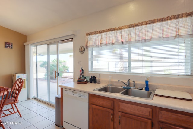 kitchen with light tile patterned flooring, dishwasher, sink, and vaulted ceiling