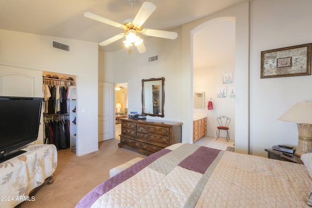 carpeted bedroom featuring ceiling fan, a spacious closet, ensuite bathroom, a high ceiling, and a closet