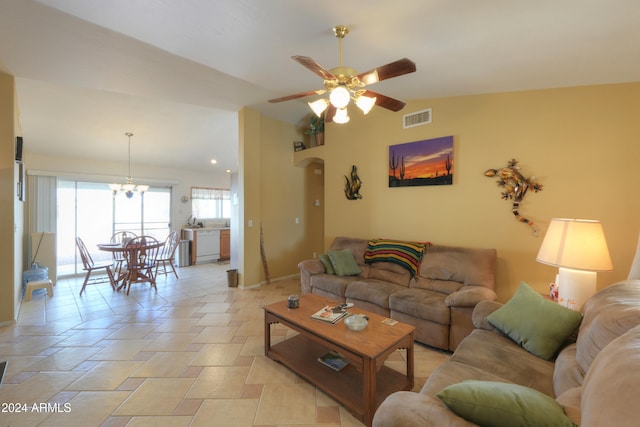 living room with lofted ceiling and ceiling fan with notable chandelier