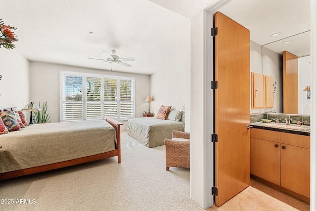 bedroom with light carpet, ceiling fan, and a sink