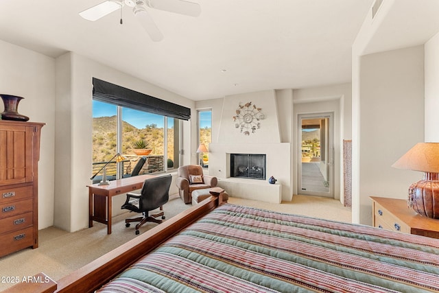 bedroom featuring light colored carpet, a fireplace with raised hearth, visible vents, a ceiling fan, and access to outside