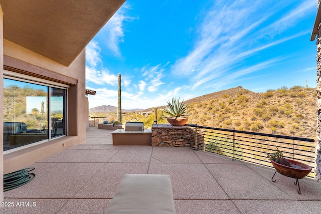 view of patio featuring a mountain view and a balcony