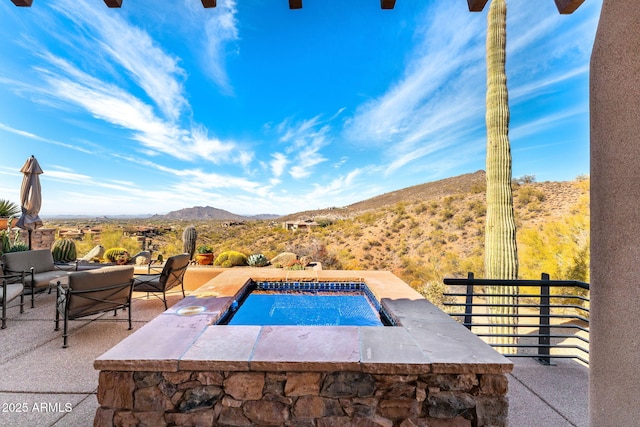 view of swimming pool with an in ground hot tub, a swimming pool, a patio area, and a mountain view