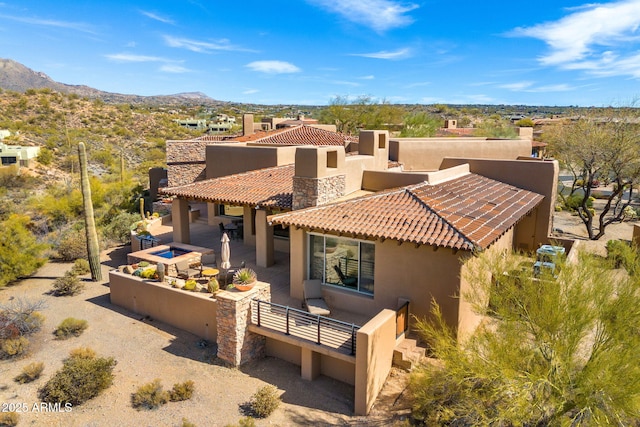 rear view of house with a patio area, a tiled roof, a mountain view, and stucco siding