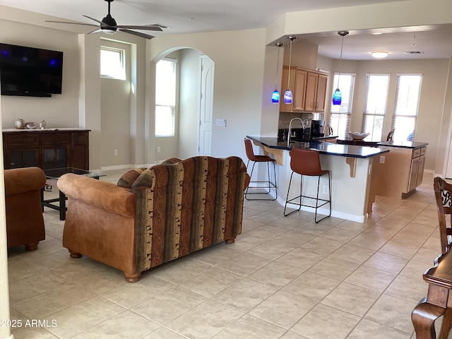 living room featuring ceiling fan, light tile patterned floors, and sink