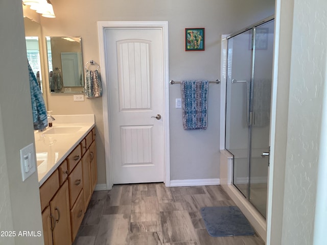 bathroom featuring hardwood / wood-style floors, a shower with door, and vanity