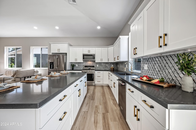 kitchen featuring stainless steel appliances, white cabinetry, tasteful backsplash, and light wood-type flooring