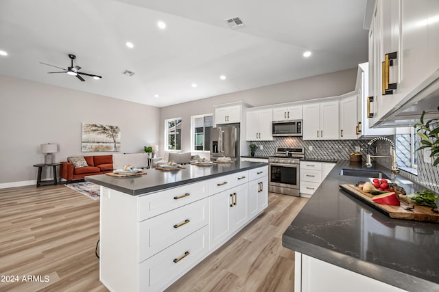 kitchen with light hardwood / wood-style floors, stainless steel appliances, ceiling fan, white cabinetry, and a center island