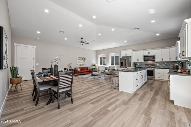 kitchen featuring appliances with stainless steel finishes, white cabinetry, a center island, and light wood-type flooring