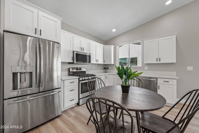 kitchen featuring stainless steel appliances, light hardwood / wood-style floors, white cabinets, and lofted ceiling