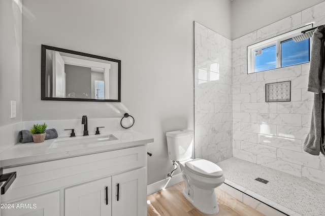 bathroom with tiled shower, hardwood / wood-style flooring, vanity, and toilet