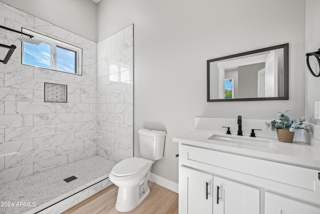 bathroom with tiled shower, a wealth of natural light, vanity, and toilet