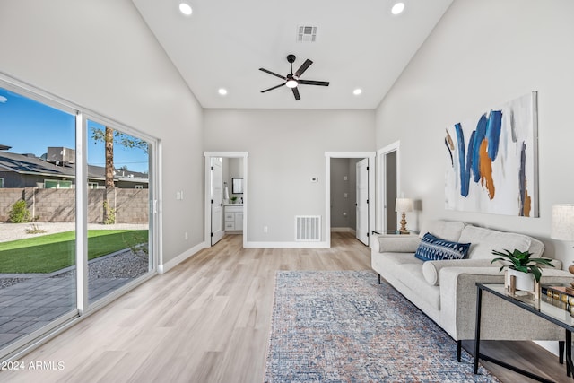 living room with a high ceiling, ceiling fan, and light hardwood / wood-style floors