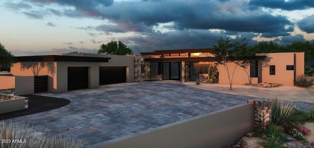 view of front of home with stucco siding, decorative driveway, and a garage