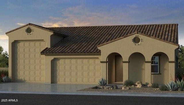 mediterranean / spanish house featuring driveway, a tiled roof, an attached garage, and stucco siding