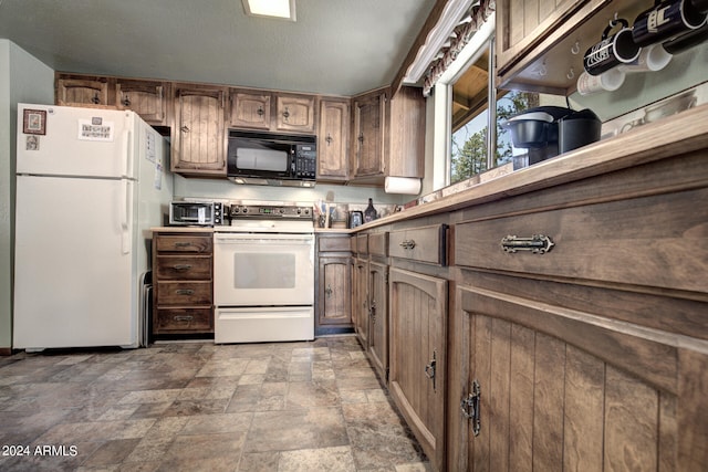 kitchen with a textured ceiling, white appliances, and tile floors