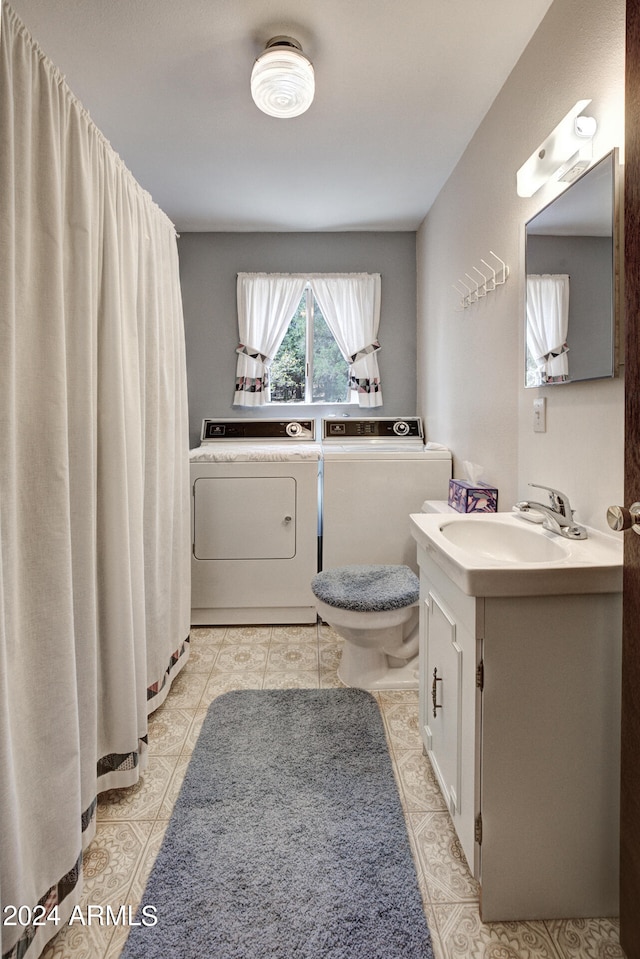 bathroom with tile flooring, washing machine and dryer, large vanity, and toilet