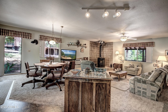 living room featuring a textured ceiling, ceiling fan, a wood stove, and rail lighting