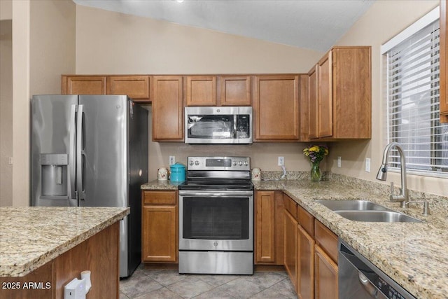 kitchen with light stone countertops, appliances with stainless steel finishes, vaulted ceiling, sink, and light tile patterned flooring