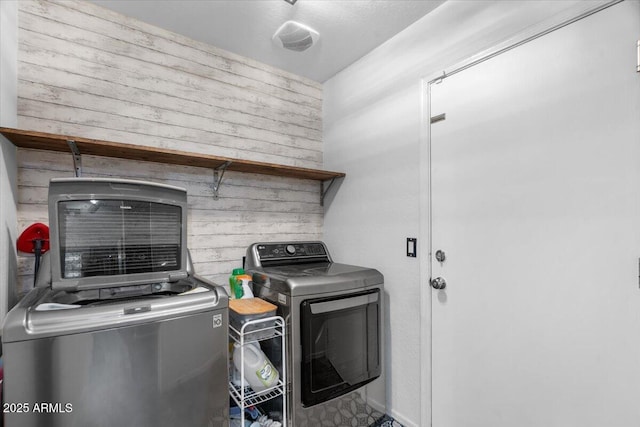 laundry area featuring washing machine and dryer and wooden walls