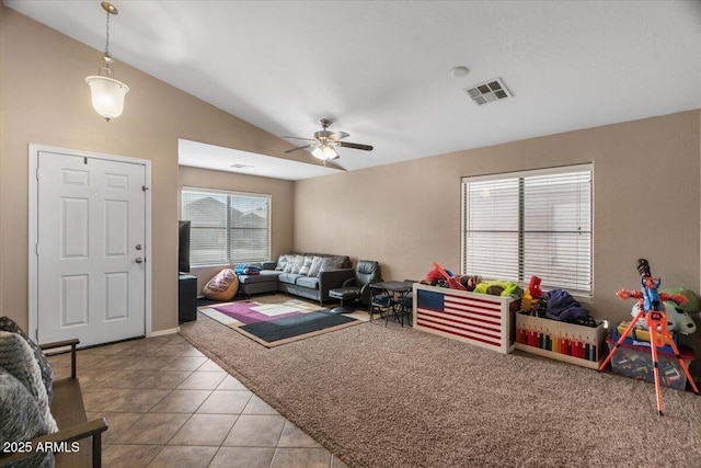 living room with ceiling fan, light tile patterned floors, and vaulted ceiling