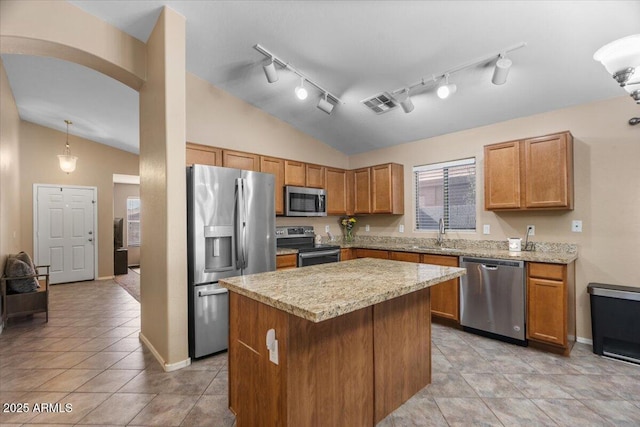 kitchen featuring lofted ceiling, a kitchen island, decorative light fixtures, stainless steel appliances, and sink