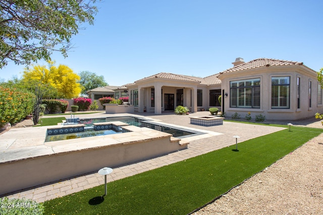 back of house featuring an in ground hot tub and a patio