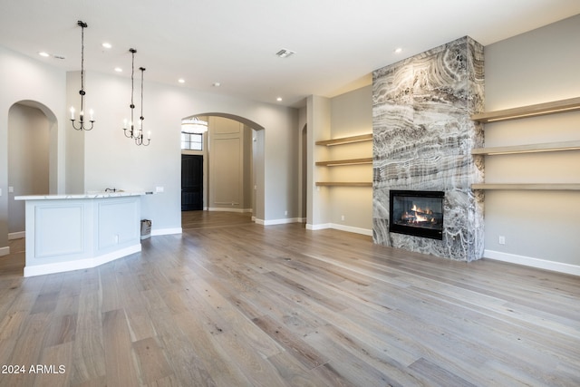 unfurnished living room with a fireplace, light hardwood / wood-style flooring, and an inviting chandelier