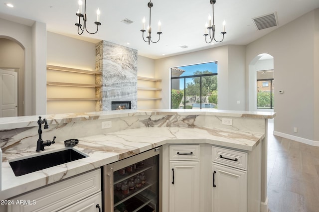 kitchen featuring light hardwood / wood-style floors, wine cooler, white cabinetry, and sink