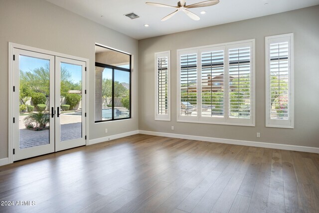 empty room featuring plenty of natural light, wood-type flooring, and french doors