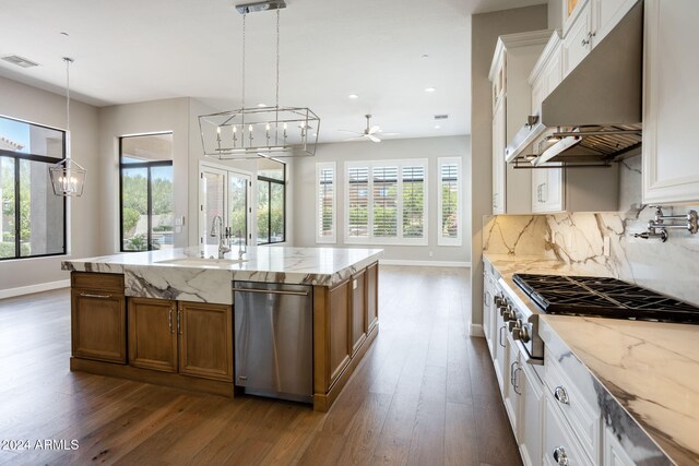 kitchen with white cabinets, plenty of natural light, and an island with sink