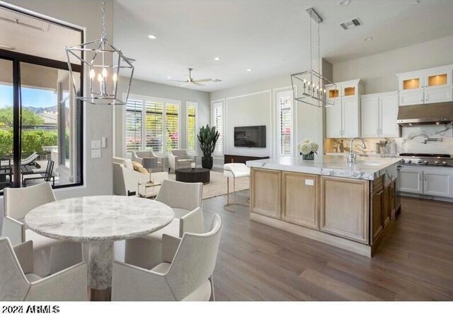 kitchen featuring hanging light fixtures, white cabinets, a kitchen island with sink, and ceiling fan