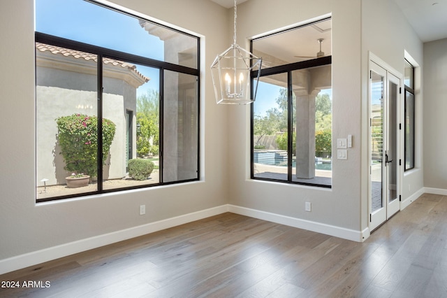 unfurnished room featuring hardwood / wood-style floors, ceiling fan with notable chandelier, and french doors