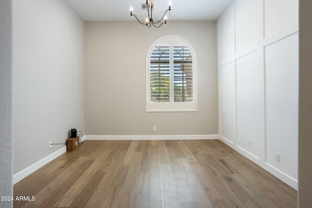 empty room with a chandelier and light hardwood / wood-style floors