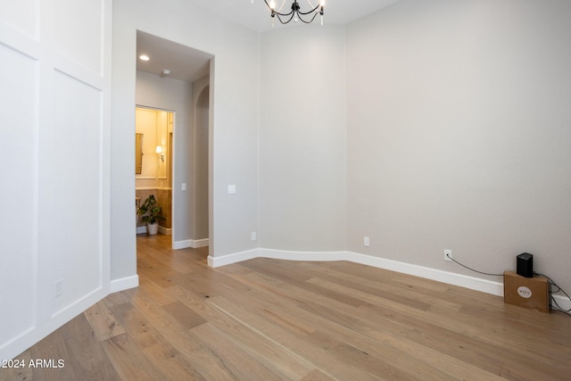 spare room with an inviting chandelier and light hardwood / wood-style flooring