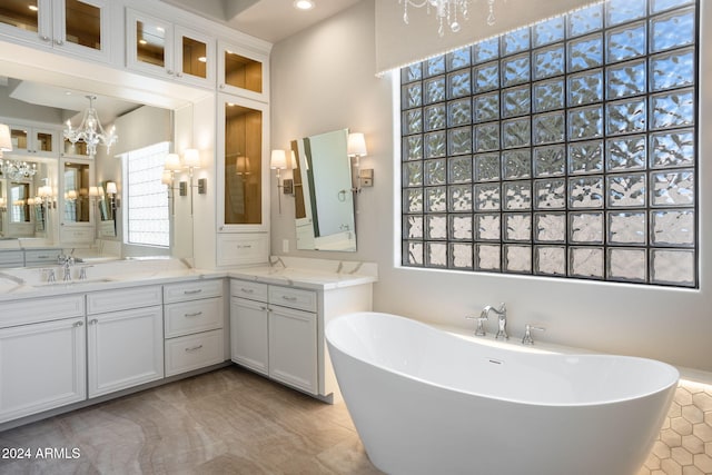 bathroom with a chandelier, vanity, a bathing tub, and tile patterned flooring