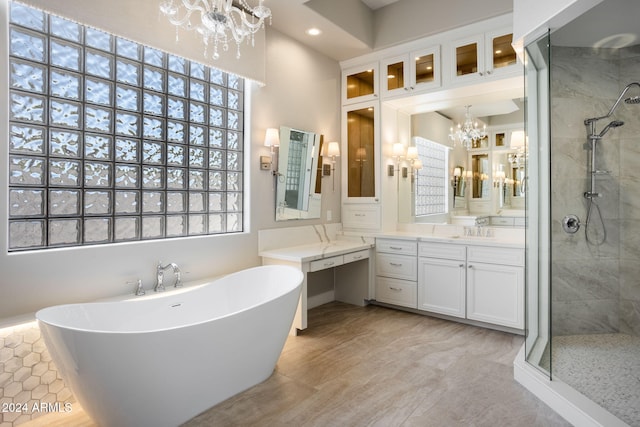 bathroom with vanity, independent shower and bath, and a chandelier