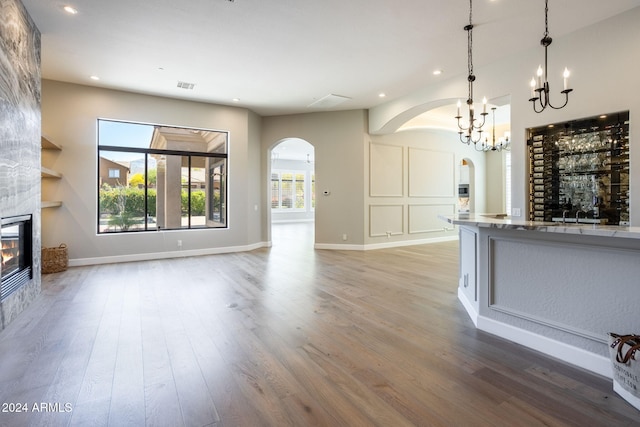 unfurnished living room featuring a fireplace, a chandelier, and hardwood / wood-style flooring