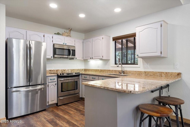 4170 Apache Dr, Happy Jack, AZ 86024 - kitchen featuring stainless steel appliances, a sink, a peninsula, a breakfast bar, and dark wood-type flooring