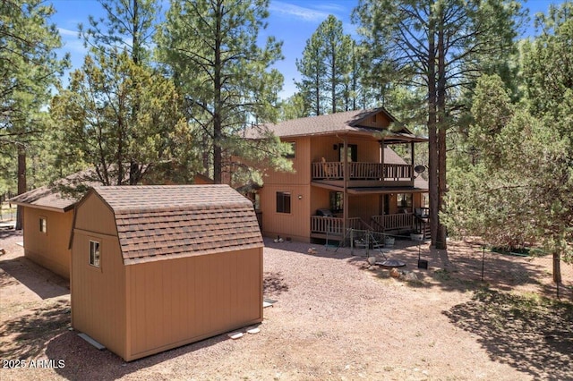 4170 Apache Dr, Happy Jack, AZ 86024 - back of property with an outdoor structure, a storage shed, a balcony, roof with shingles, and a gambrel roof
