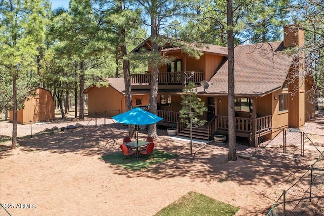 4170 Apache Dr, Happy Jack, AZ 86024 - rear view of property with a shingled roof, a shed, an outdoor structure, a balcony, and a chimney