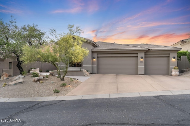 view of front of house featuring a tile roof, a garage, stucco siding, and driveway